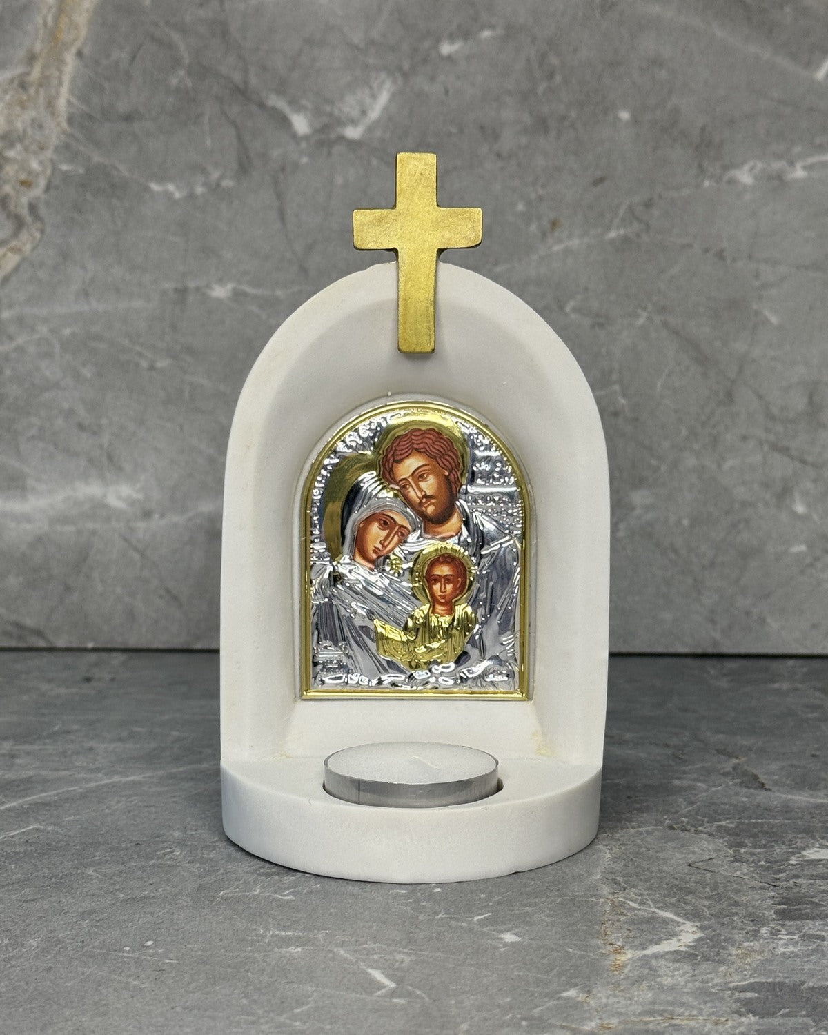 White stone Orthodox candle altar with gold cross and Holy Family icon